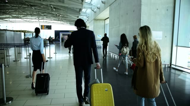 Multi-ethnic-travelers-walking-on-airport-corridor-towards-gate
