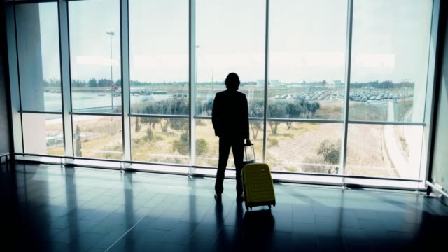 Joven-empresario-en-juego-mirando-por-la-ventana-internacional-Aeropuerto