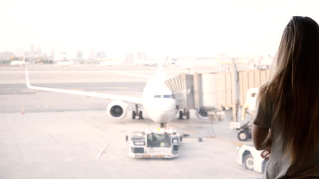 Schönes-Kaukasische-Mädchen-mit-langen-Haaren-geht-auf-Flughafen-terminal-Fenster-und-wartet,-Flugzeug-im-Hintergrund
