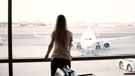 Viajero-mujer-irreconocible-con-la-bolsa-sube-a-ventana-de-terminal-Aeropuerto-salón-para-disfrutar-de-la-vista-de-aviones