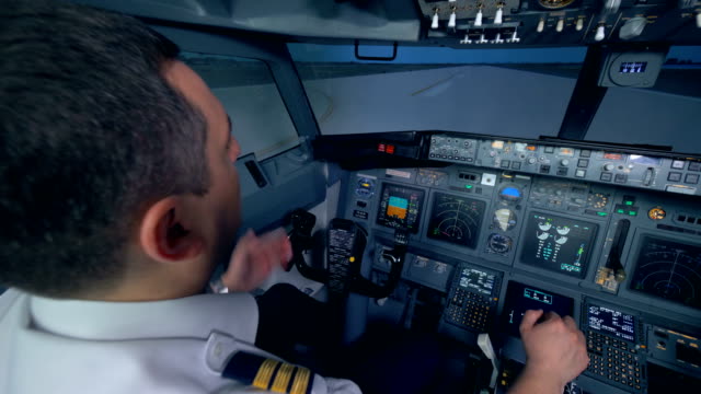 A-plane-goes-on-a-runway,-two-pilots-in-a-flight-simulator-cockpit.