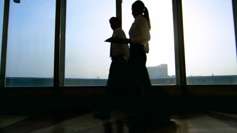 Silhouetten-von-Geschäftsleuten-zu-Fuß-vor-dem-Panoramafenster