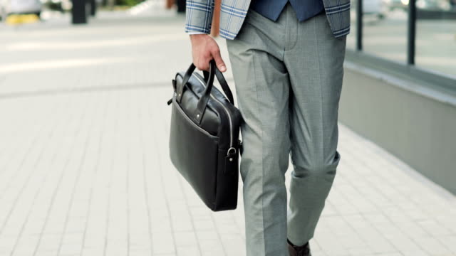 Hombre-de-negocios-con-un-maletín-caminando-por-las-calles-del-distrito-de-negocios