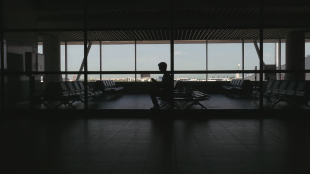 Silhouette-der-Passagier-sitzt-in-einem-Flughafen-warten-Bereich-und-Surfen-im-Internet