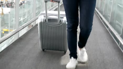 Close-up-of-woman-walking-with-trolley-suitcase-at-airport.-People-and-lifestyles-concept.-Front-view-and-low-angle