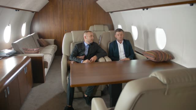 Two-businessmen-talking,-sitting-in-private-jet