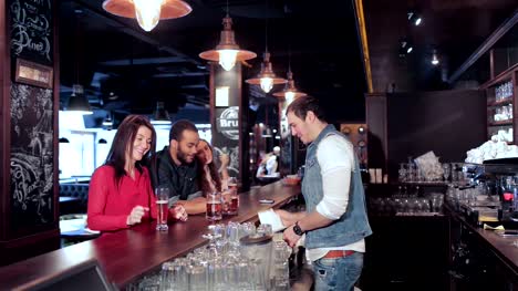Two-cute-girls-and-a-guy-get-his-order-from-the-bartender