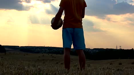 man-playing-with-a-ball-in-a-field-at-sunset,-man-playing-football-at-dawn