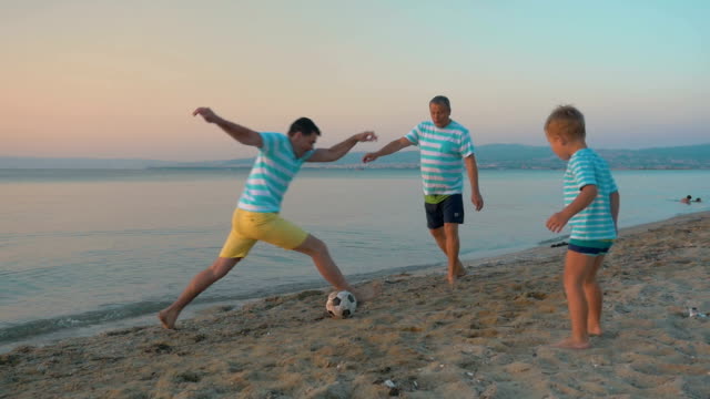 Männer-und-Junge-spielt-Fußball-am-Strand