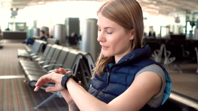 Beautiful-attractive-young-woman-using-smartwatch-in-airport.-Sending-voice-message-to-friend