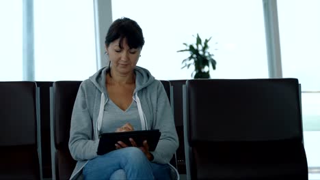Woman-using-a-digital-tablet-in-airport-waiting-area