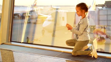 Adorable-little-girl-playing-with-small-model-airplane-in-airport-waiting-for-boarding.-Concept-of-flying-and-airplane.