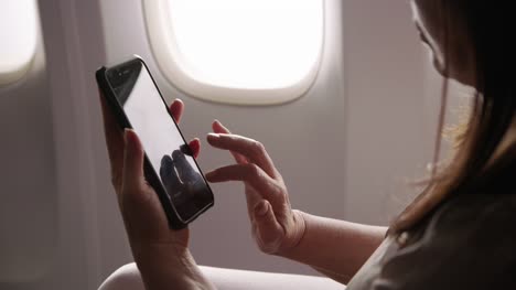 Closeup-of-woman-using-cell-phone-on-airplane