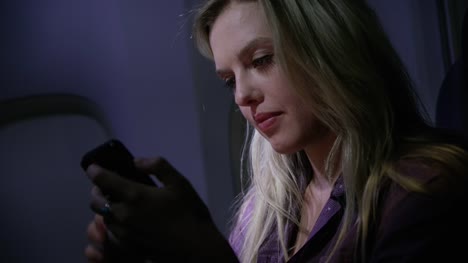Closeup-of-young-woman-using-cell-phone-on-airplane