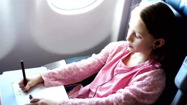 Entzückende-kleine-Mädchen-mit-dem-Flugzeug-reisen.-Kid-Zeichnung-Bild-mit-bunten-Stiften,-die-sitzen-in-der-Nähe-von-Fenster