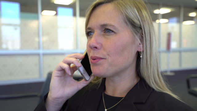 Mujer-de-negocios-hablando-por-teléfono-celular-en-el-aeropuerto