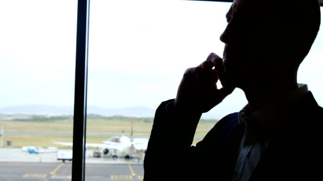 Businessman-talking-on-mobile-phone-at-airport
