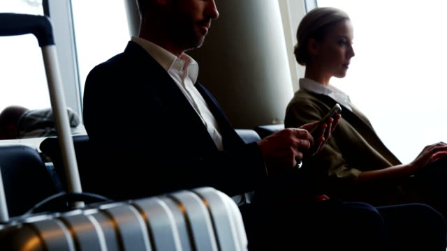 Businessman-texting-on-mobile-phone-while-waiting-at-airport