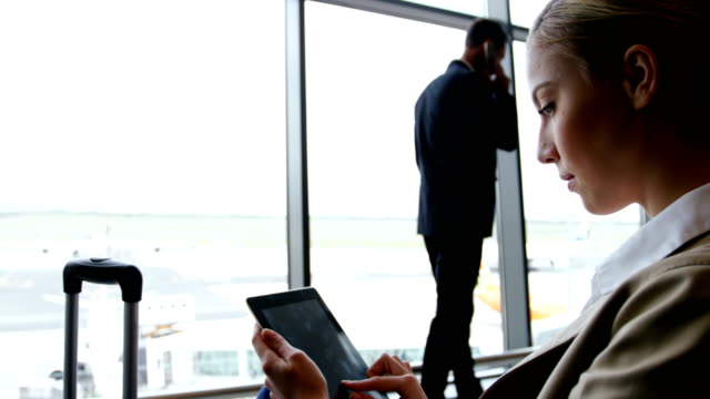Businesswoman-using-digital-tablet-and-smiling-at-airport