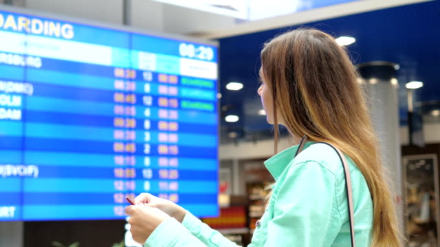 Young-Woman-Looks-At-The-Information-Board-Of-Departures-At-The-Airport.