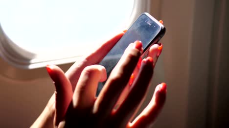 Nahaufnahme-von-Frauenhand-telefonieren,-sitzen-am-Fenster-des-Flugzeugs