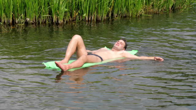 Den-Mann-ruhen-In-den-heißen-Sommertag-im-Fluss-schwimmen-auf-der-Matratze.