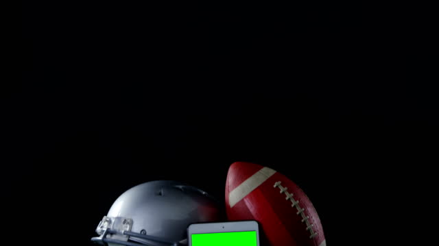 Close-up-of-football,-mobile-phone-and-head-gear-on-artificial-turf-4k
