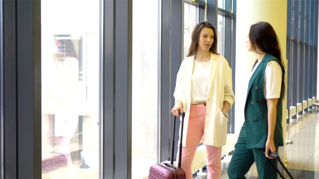 Junge-Frauen-mit-Gepäck-im-Flughafen-zu-Fuß-mit-ihrem-Gepäck.-Fluggäste-in-einer-Flughafen-Lounge-wartet-auf-Flug-Flugzeug