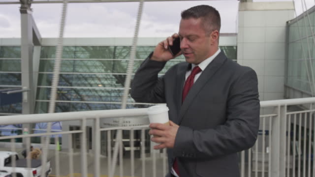 Geschäftsmann-zu-Fuß-und-reden-über-Handy-am-Flughafen