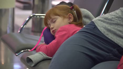 girl-and-momsleeping-at-the-airport-waiting-area.-flight-delay