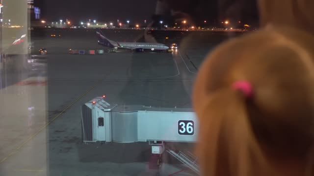 A-little-girl-with-mom-looks-at-the-planes-at-the-airport