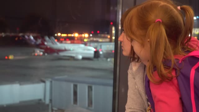 A-little-girl-with-mom-looks-at-the-airplanes-at-the-airport