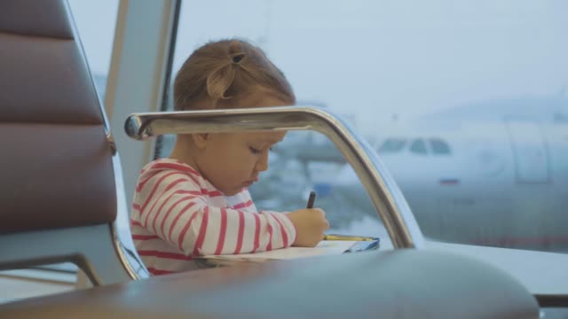 Niña-bebé-basándose-en-el-aeropuerto-con-el-avión-en-el-fondo