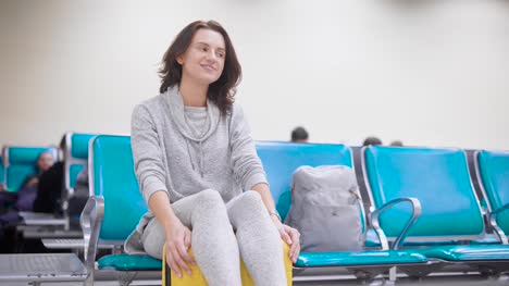 Mujer-joven-alegre-y-feliz-está-sentado-en-su-equipaje-y-riendo