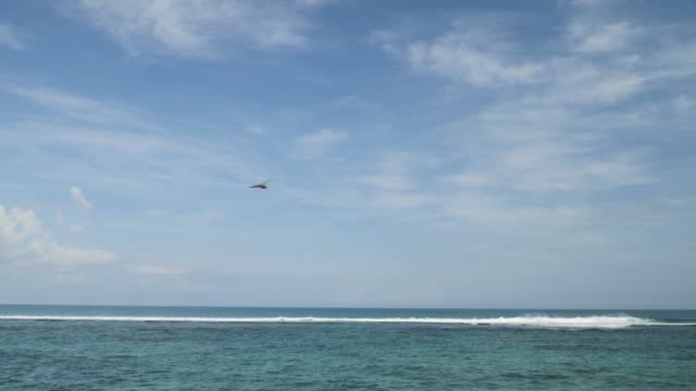 Airplane-landing-on-island-Bali-airport-under-blue-sea-with-waves-on-the-horizon