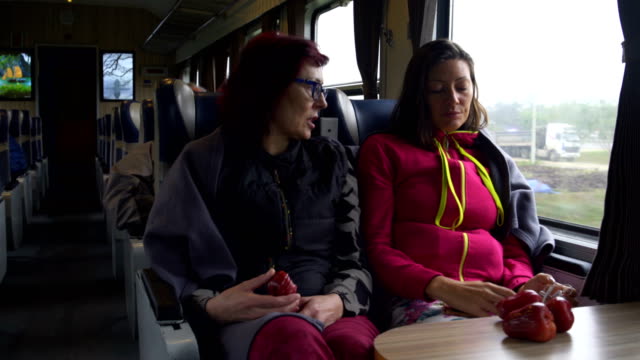 Women-go-on-the-train,-talk-and-eat-fruit