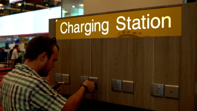 A-man-is-charging-a-smartphone-on-the-charging-station-at-the-airport