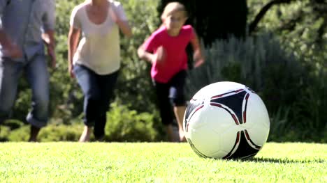 Familie-Laufen-zu-Kick-Fußball-im-Garten