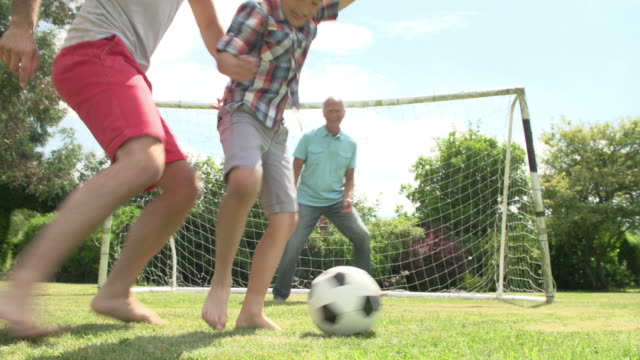 Großvater-und-Enkel-und-Vater-spielen-Fußball-im-Garten