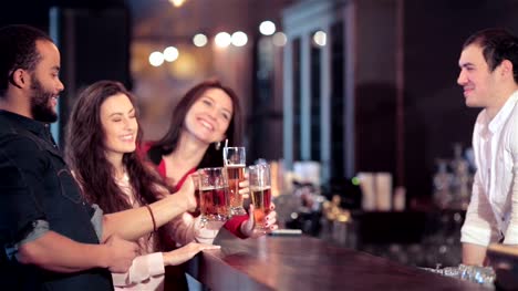 Cheerful-company-of-girls-and-a-guy-at-the-bar-lifts-up-a-glass-of-beer