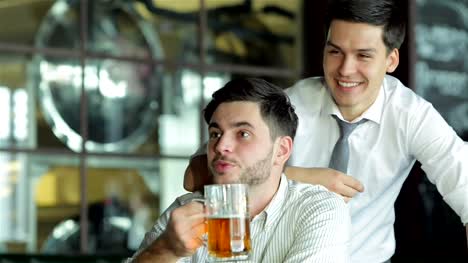Two-successful-friends-businessmen-drink-beer-and-rejoice-and-shout-together