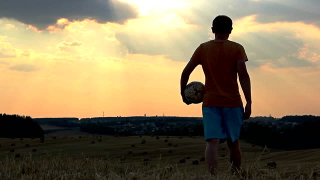 Mann-spielen-mit-einem-ball-in-einem-Feld-bei-Sonnenuntergang,-Mann-spielen-Fußball-im-Morgengrauen