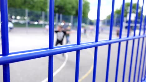 children-playing-football-behind-a-metal-fence