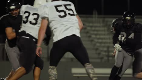 A-football-player-fights-his-way-down-the-field-toward-the-end-zone-at-night