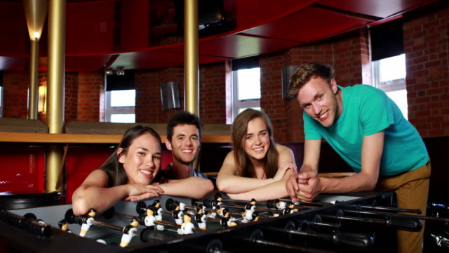Attractive-friends-posing-on-table-football
