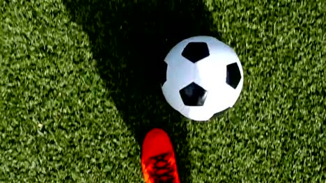 Footballer-with-orange-shoes-leading-the-ball,-top-view