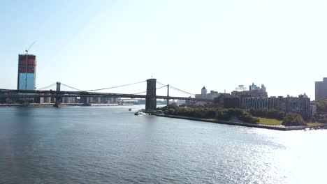 Vista-aérea-del-puente-de-Brooklyn-a-través-del-East-river-en-Nueva-York,-América.-Drone-volando-sobre-el-agua-en-el-distrito-de-Brooklyn