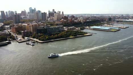 Vista-aérea-del-barco-del-montar-a-caballo-a-través-de-este-río-cerca-de-la-orilla-del-distrito-de-Brooklyn-y-el-puente-en-Nueva-York,-América