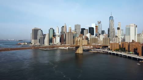 Aerial-view-of-the-capital-of-America,-New-York.-Drone-flying-up-to-the-Brooklyn-bridge-through-the-East-river