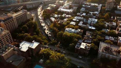 Vista-aérea-del-barrio-de-Brooklyn-en-Nueva-York,-Estados-Unidos,-Drone-volando-sobre-los-apartamentos-y-el-tráfico-por-carretera-en-puesta-de-sol